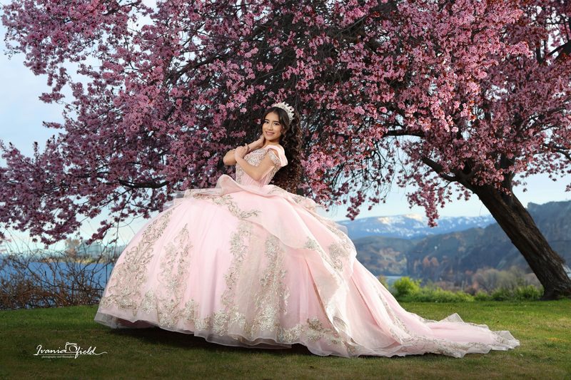 Quinceañera bajo un cerezo en flor frente al valle