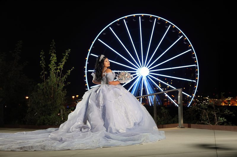 Quinceañera de noche frente a la rueda de la fortuna, fotografiada por el estudio